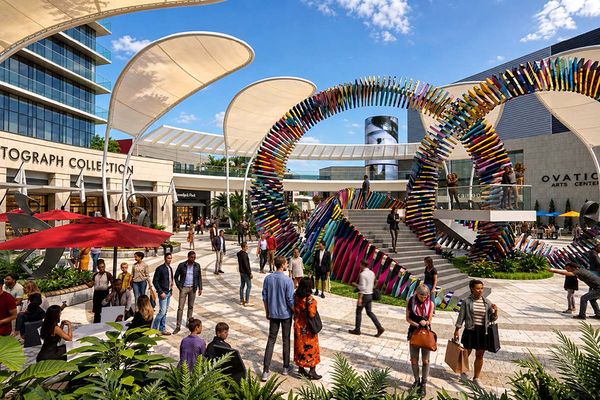 A project rendering showing sculptures, buildings, and crowds at midday.